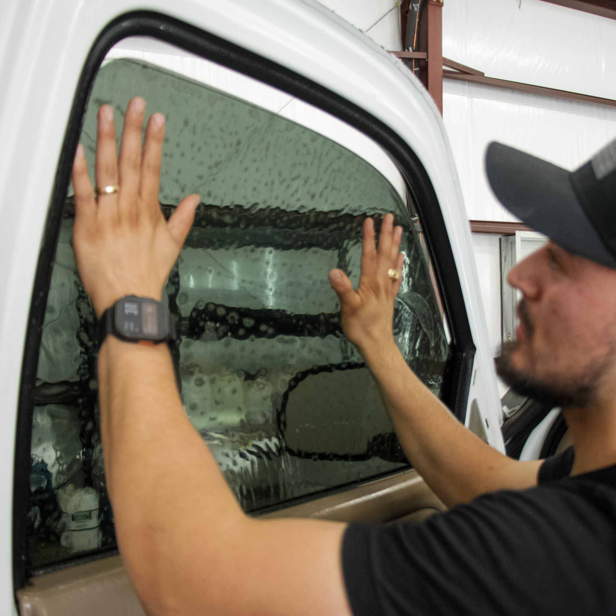 Professional window tint installer applying ceramic film to front driver-side window for heat and UV protection in College Station, TX.
