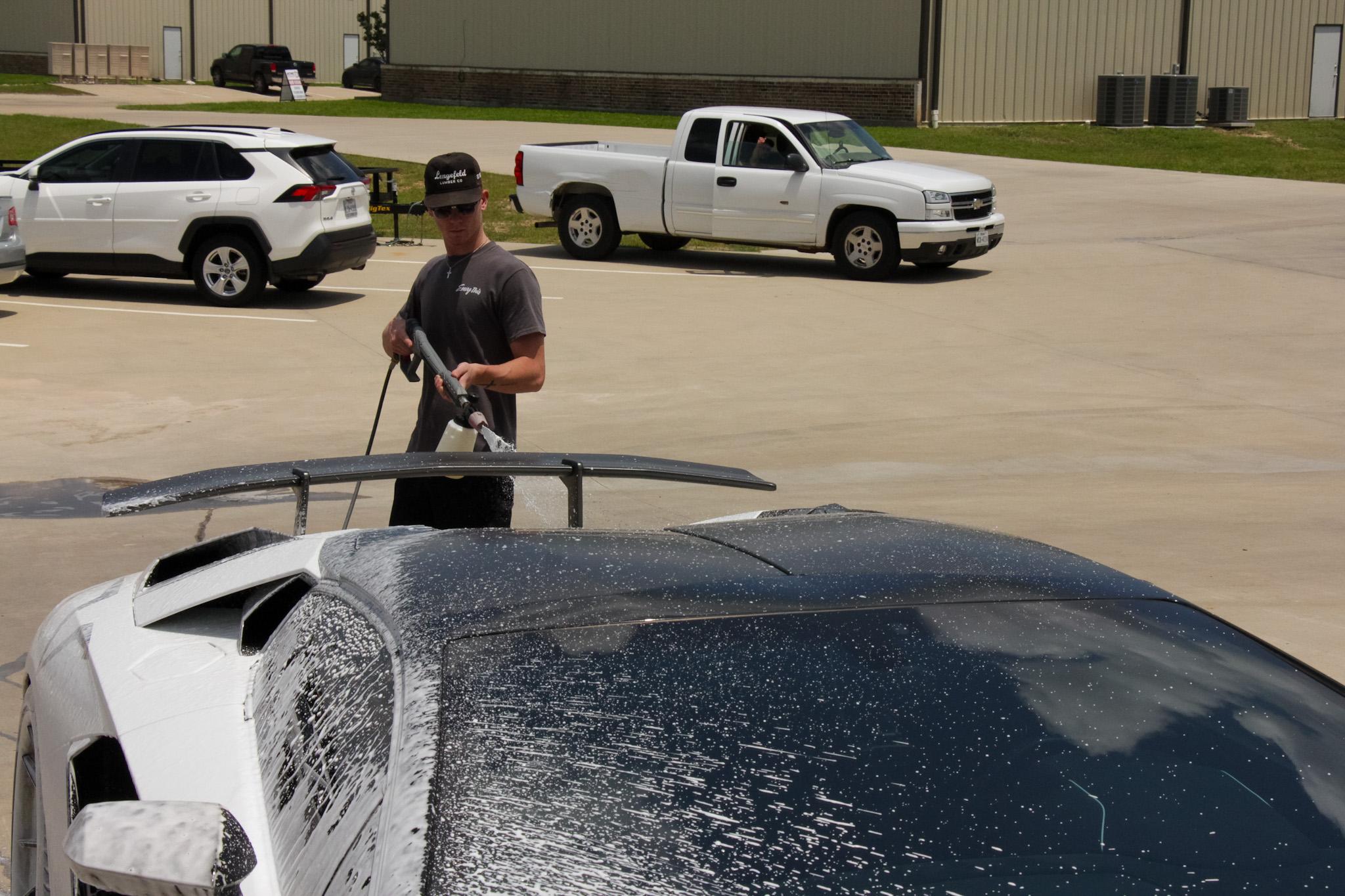 Car owner washing a vehicle with ceramic coating, demonstrating easy maintenance practices
