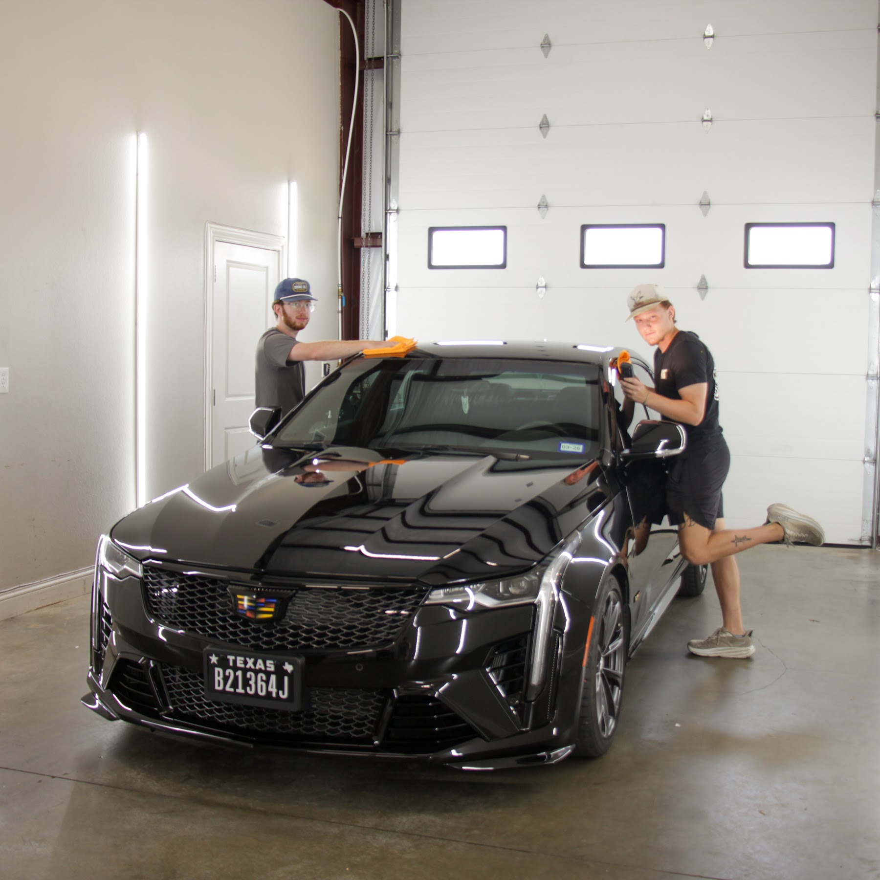 Two Envy This Detailing technicians detailing a black Cadillac CT5 in College Station, TX