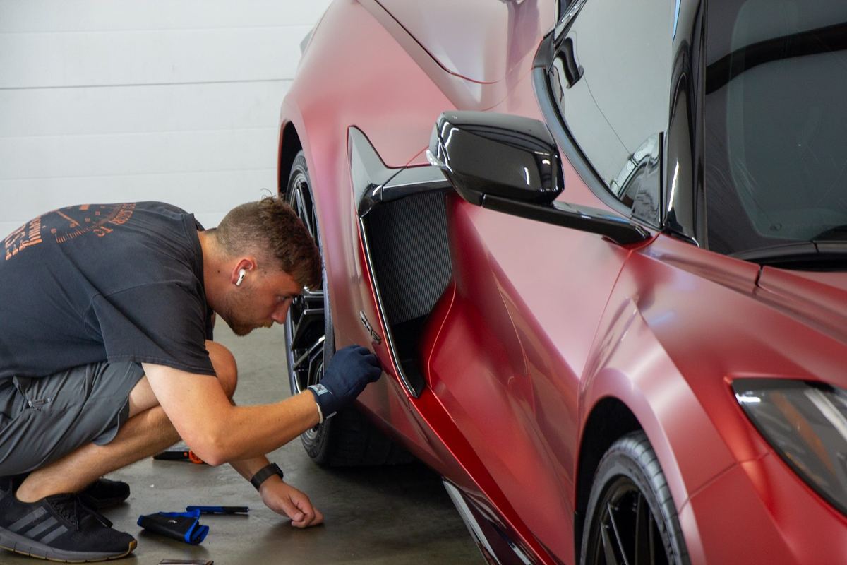 Envy This Detailing technician installing matte paint protection film on a Corvette Z06 in College Station